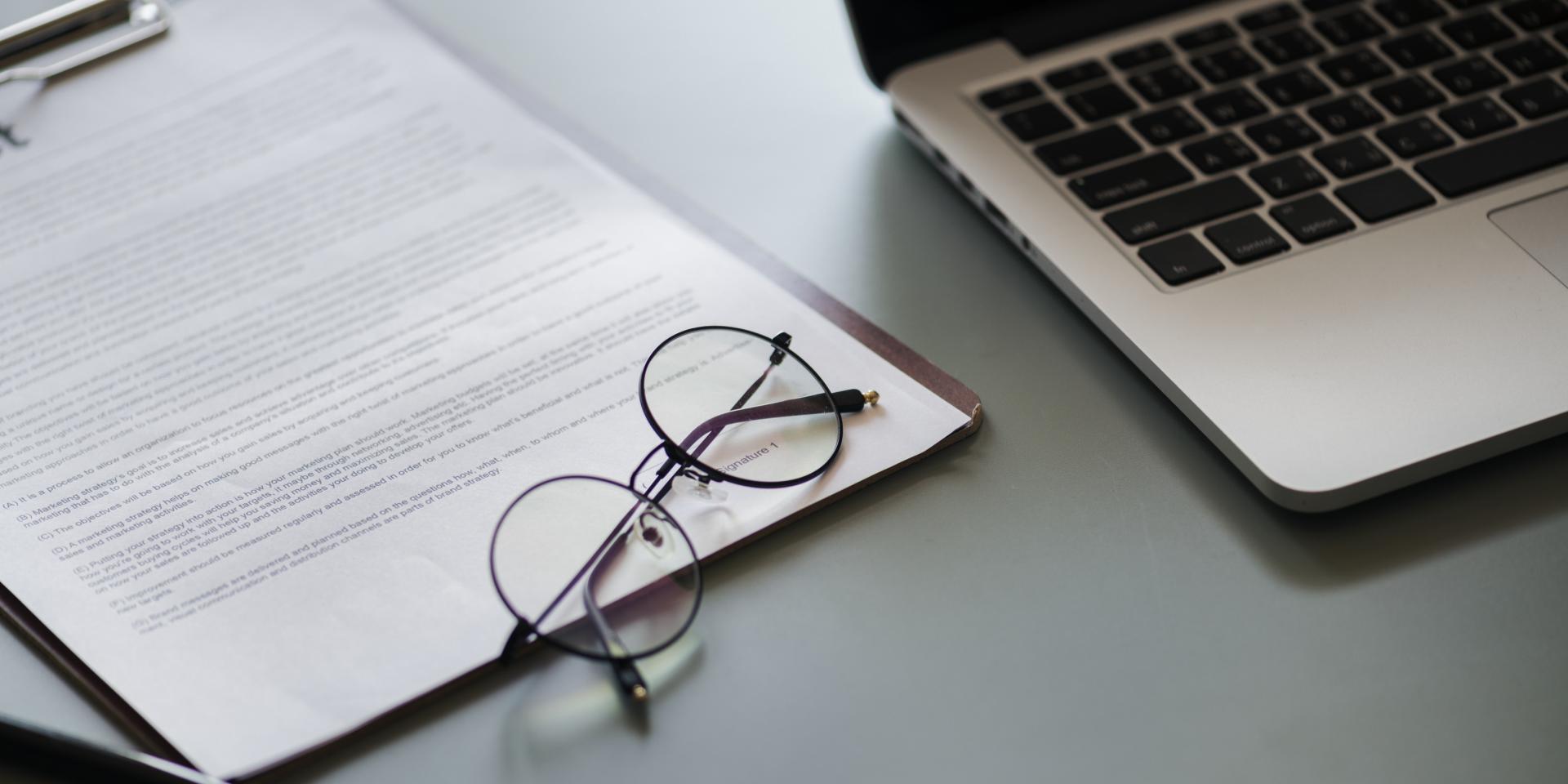 Photo of a form, a computer, and a pair of glasses