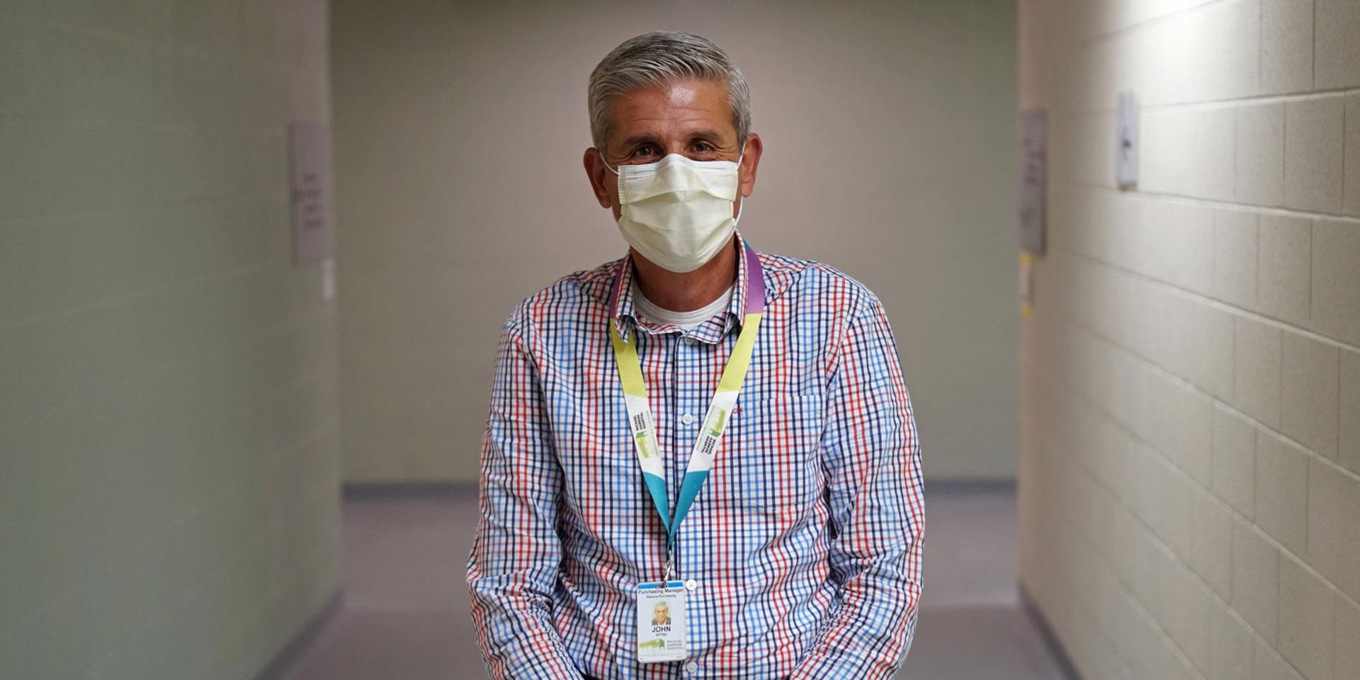 John Vittas standing in hallway wearing a mask