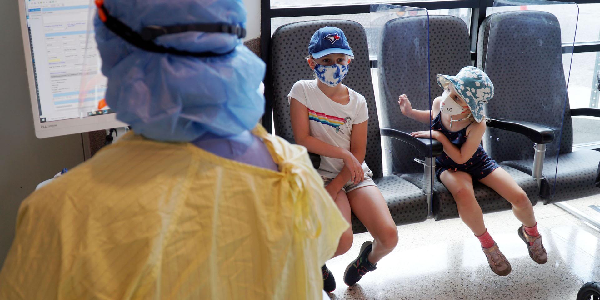 Two children wait in the new paediatric ed covid-19 assessment zone before a nurse examines them