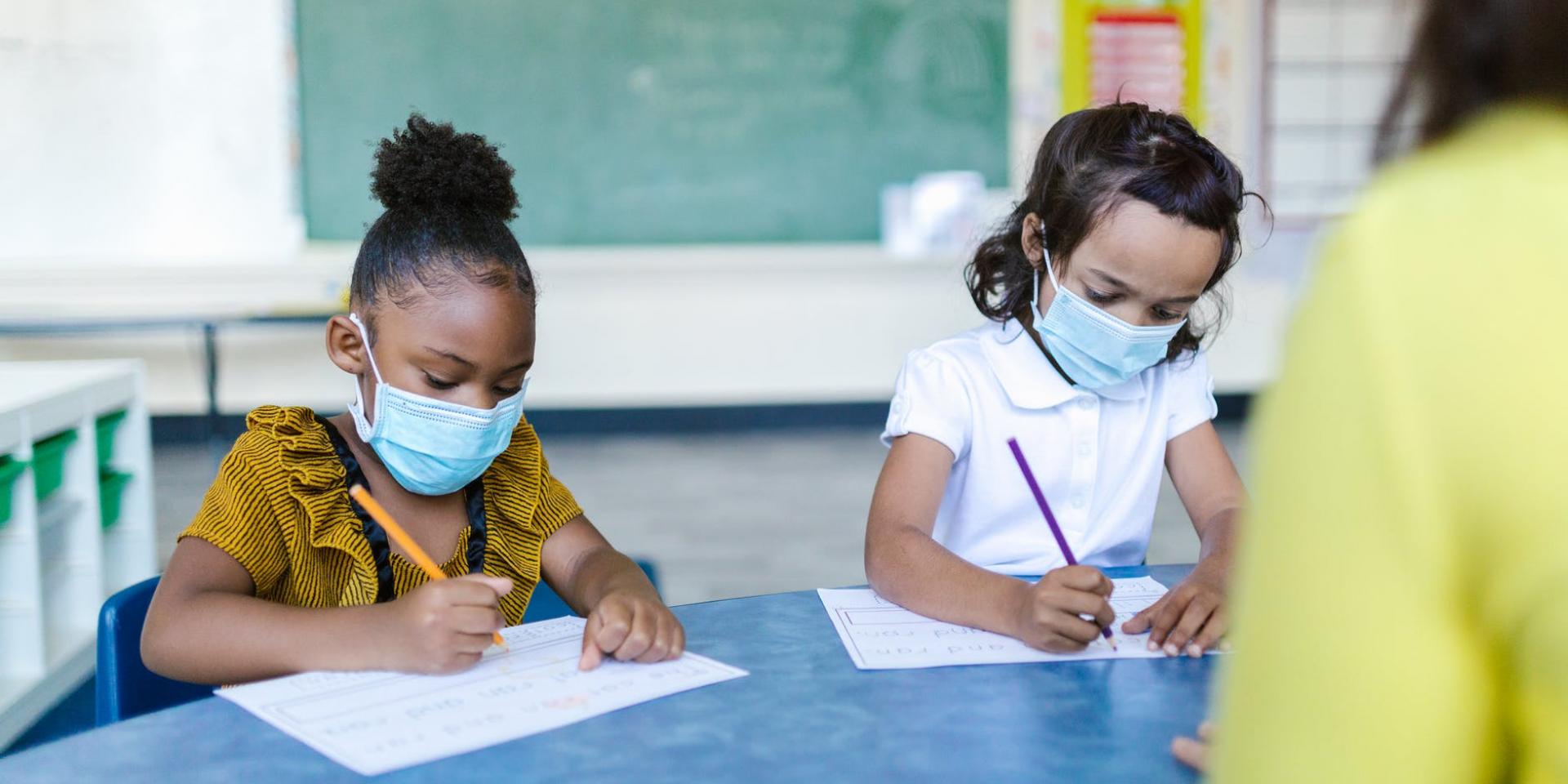 Two children sit at a desk at school.