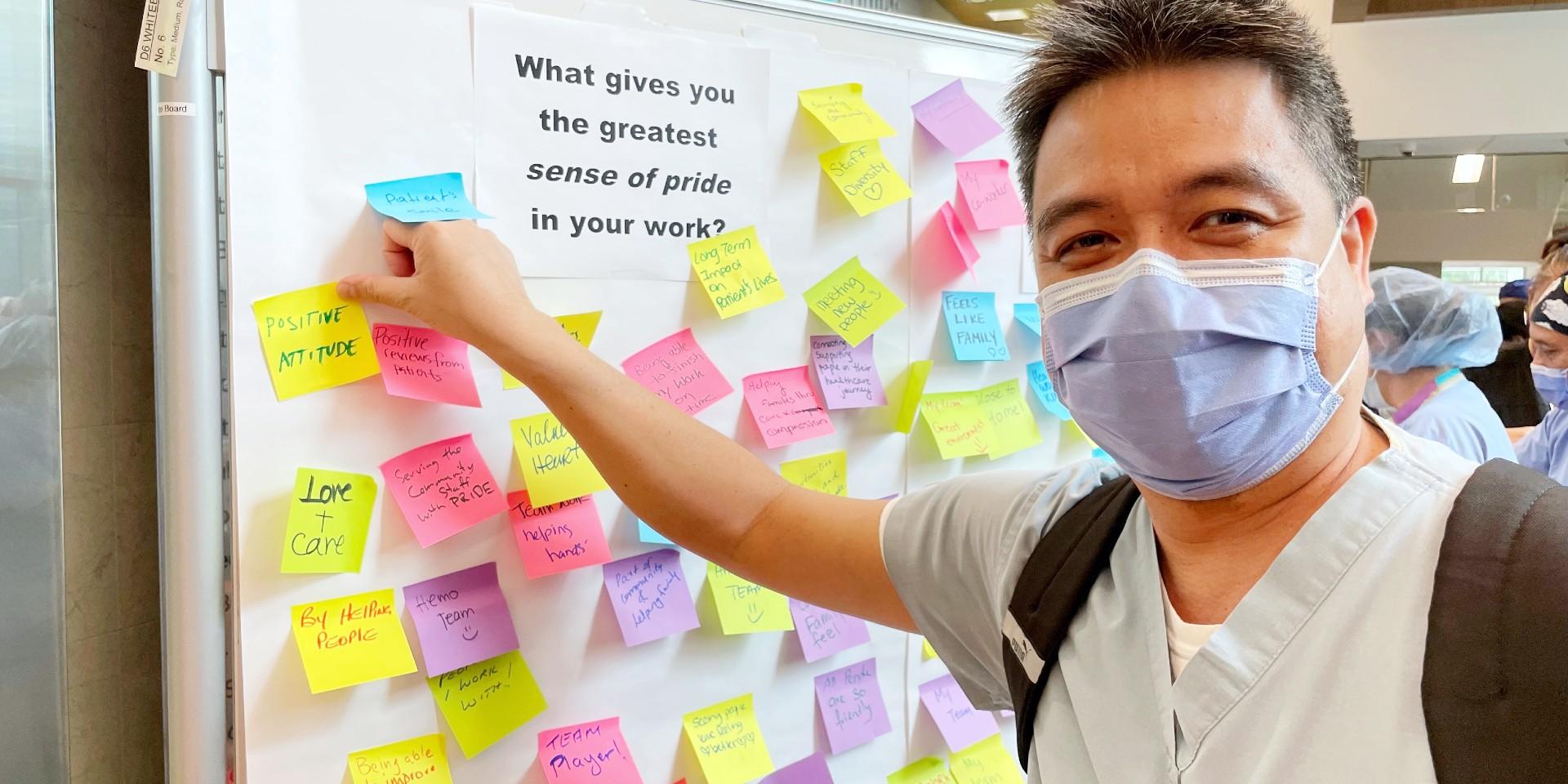 Individual places a sticky note on a whiteboard in the Ken and Marilyn Thomson Patient Care Centre