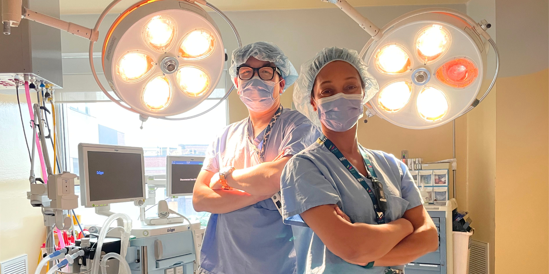 Kevin Ly and Catherine Antoine, perioperative nurses at Michael Garron Hospital. They are standing with their arms crossed in the operating room.