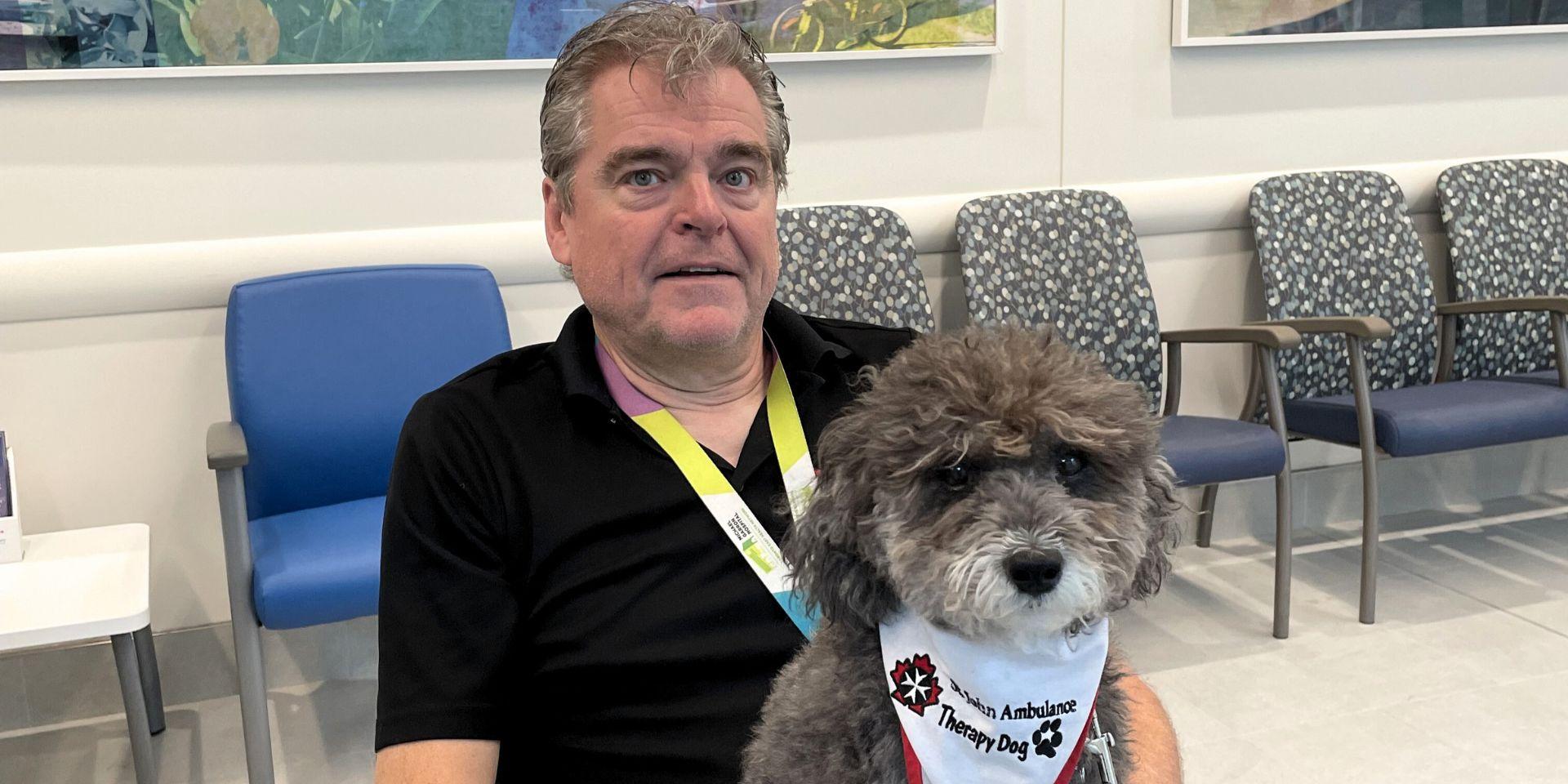 David sitting with pet therapy dog, Sprocket on his lap.