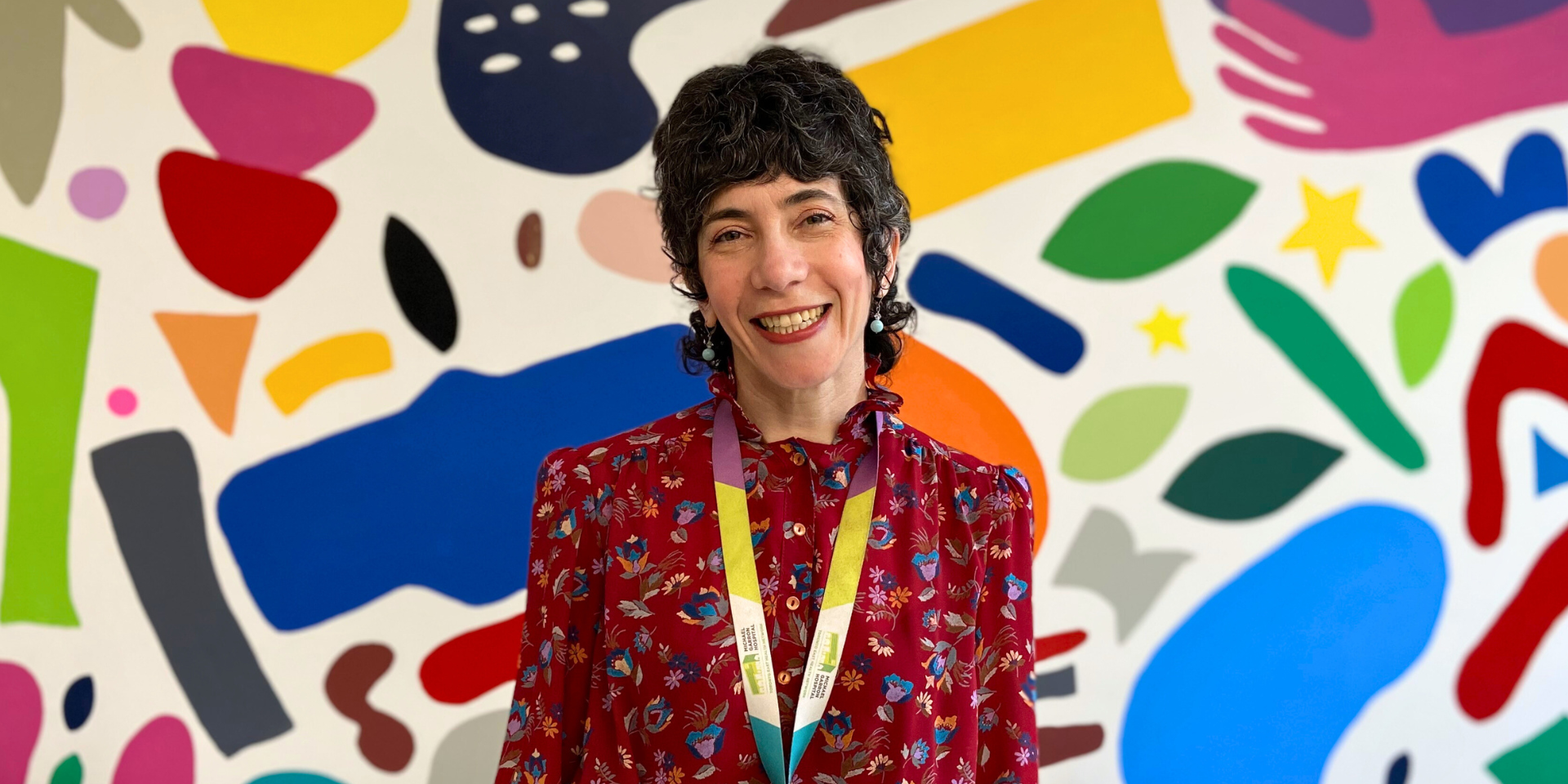 Julia King, Registered Dietitian at Michael Garron Hospital, stands in front of a colourful mural.