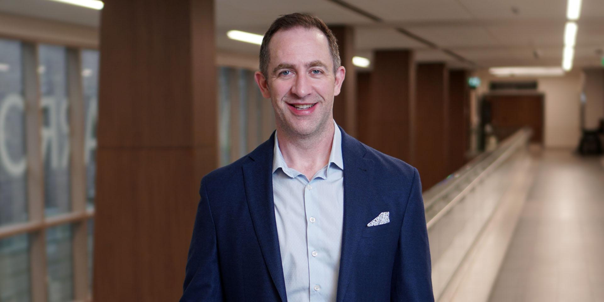 Dr. Michael Warner wearing a suit and smiling inside a hospital.