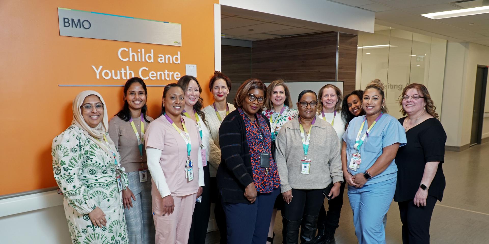 A group of Michael Garron Hospital staff pose in front of the BMO Child and Youth Centre.