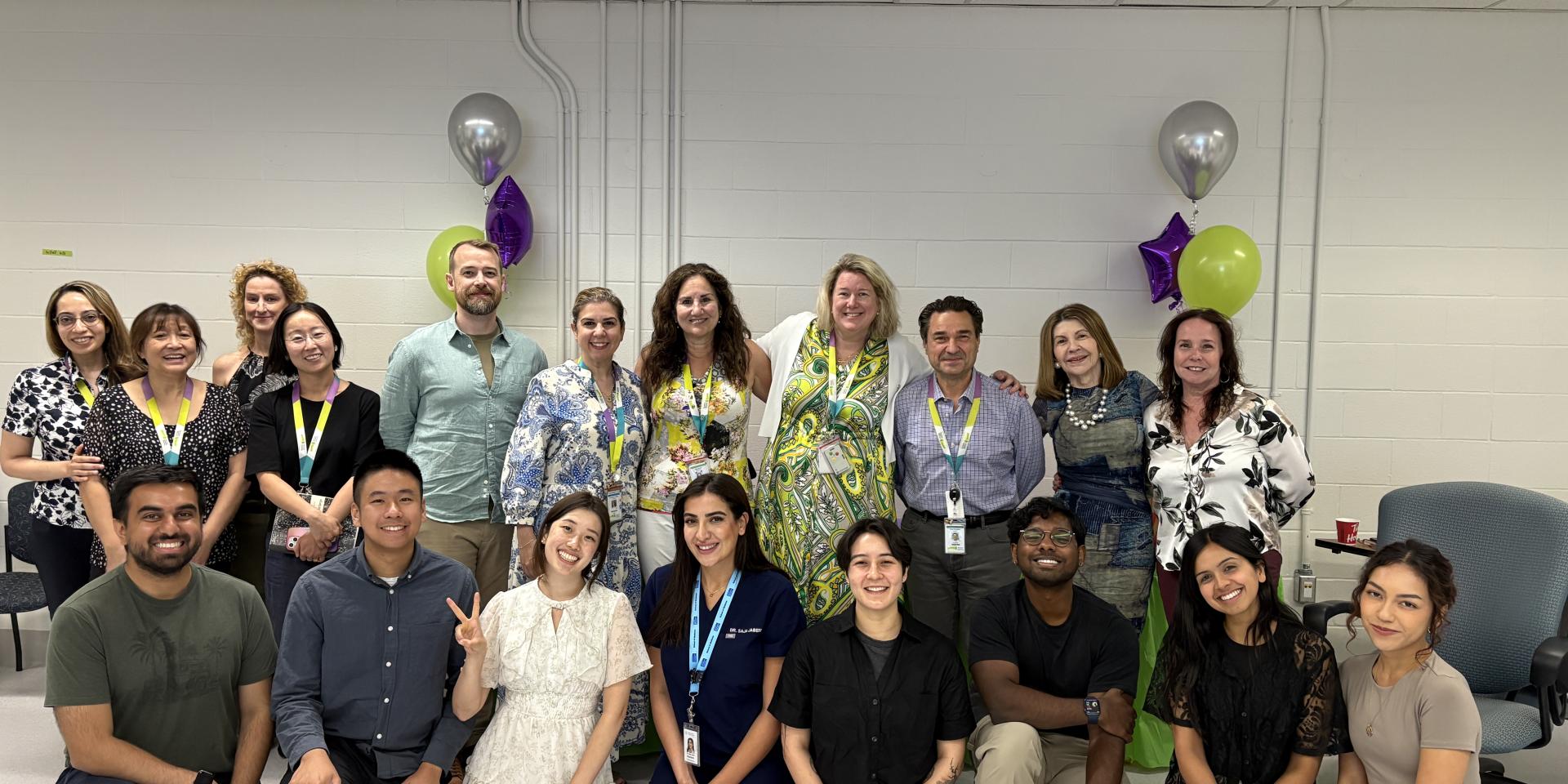 A group of medical residents stand with MGH staff smiling at the camera. 