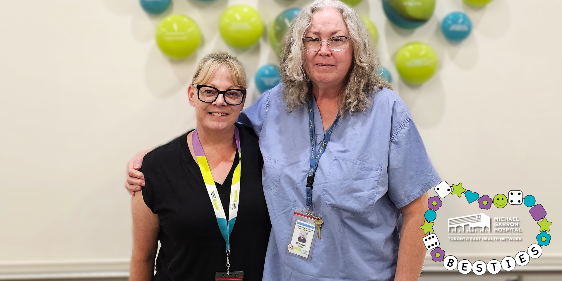 Two people stand in a hospital hallway and are smiling. 