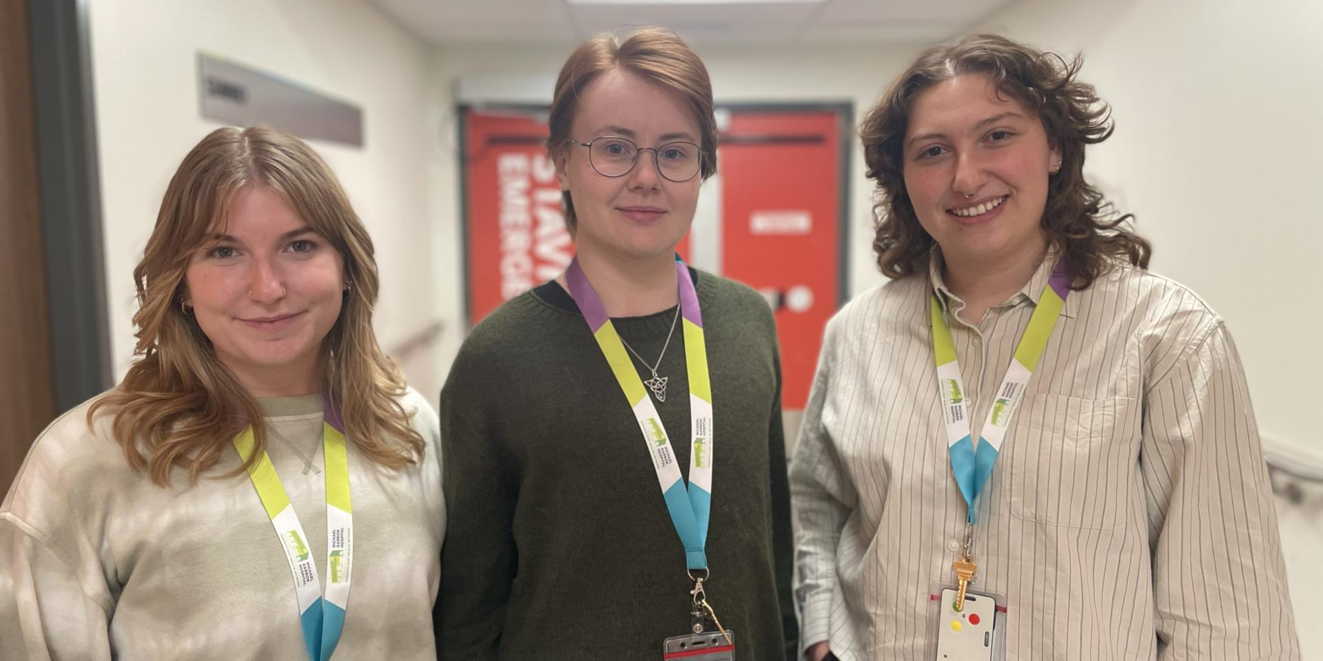 Three members of the Stavro ED peer support team pose in front of the Stavro Emergency Department at Michael Garron Hospital.