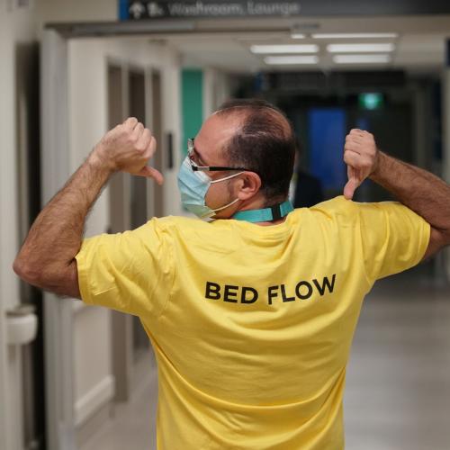Ehab Matta, Manager, Patient Access Services at MGH, points to the back of his shirt that reads "Bed Flow" in the Thomson Centre.