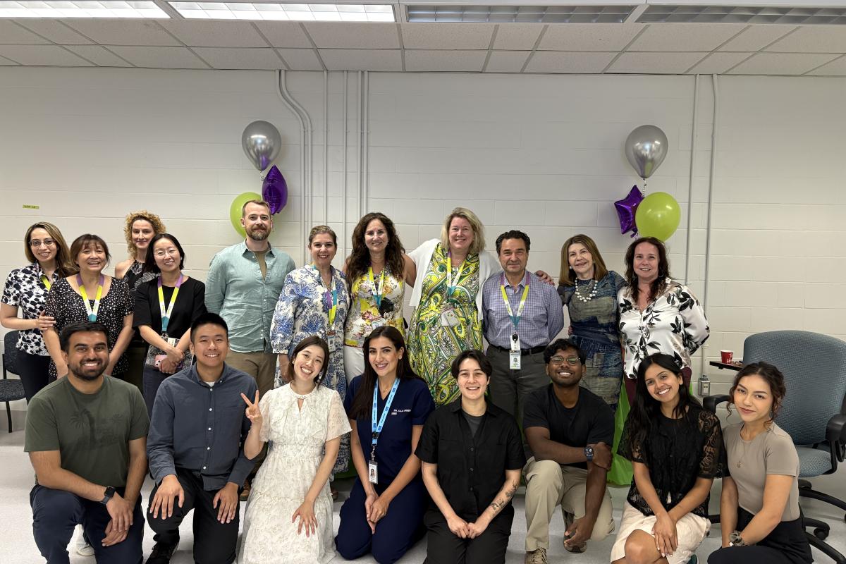 A group of medical residents stand with MGH staff smiling at the camera. 