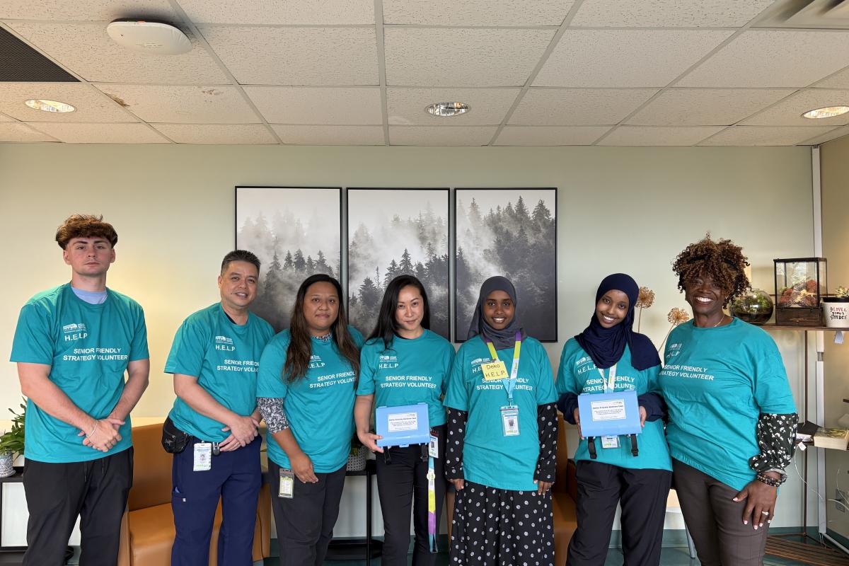 A group of volunteers in a hospital stand together while smiling at the camera 