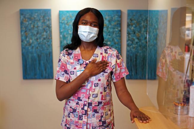 Sheryl Grant stands in her unit with her hand over her heart