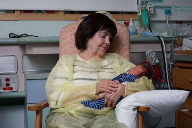 Nancy Simmons, Special Care Nursery volunteer, holds a newborn in her arms like she does every Monday during her shift.