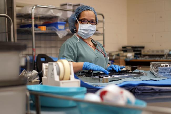 Adela wearing PPE touching a tray of instruments