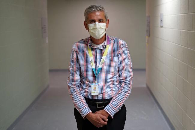 John Vittas standing in hallway wearing a mask