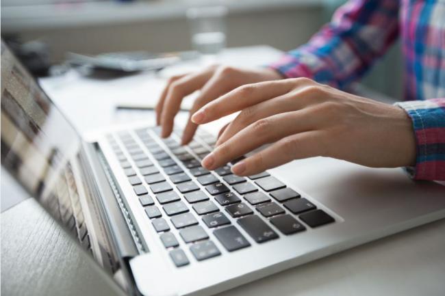 Hands typing on a laptop