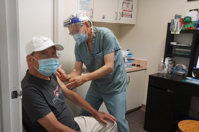 Foo Ngan, an 82-year-old East Chinatown resident, receives his second dose of the COVID-19 vaccine at the office of his family doctor, Dr. Terence Leung.