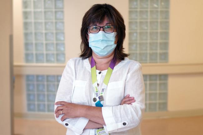 Woman stands in a hallway with her arms crossed