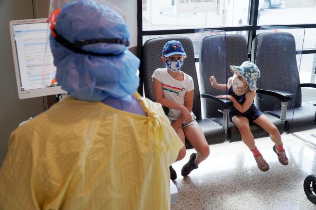 Two children wait in the new paediatric ed covid-19 assessment zone before a nurse examines them