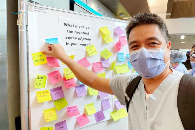 Individual places a sticky note on a whiteboard in the Ken and Marilyn Thomson Patient Care Centre