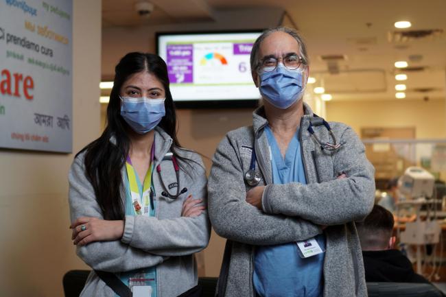 A nurse and doctor stand in front of a wait time clock in Michael Garron Hospital's Emergency Department.