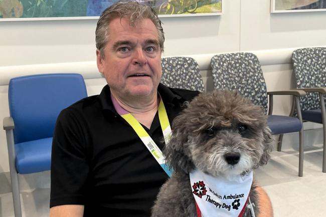 David sitting with pet therapy dog, Sprocket on his lap.