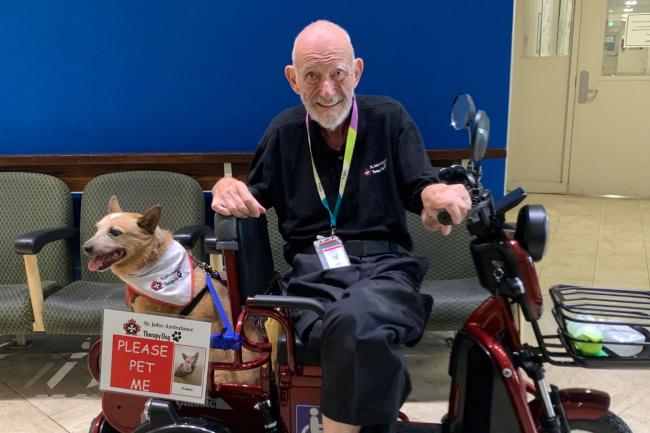 John Harper sitting on an electronic scooter with pet therapy dog Pablo