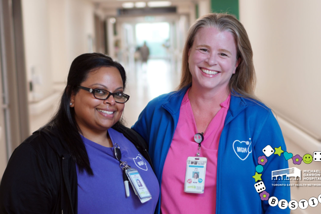 Two nurses smiling and standing in a hallway at Michael Garron Hospital.