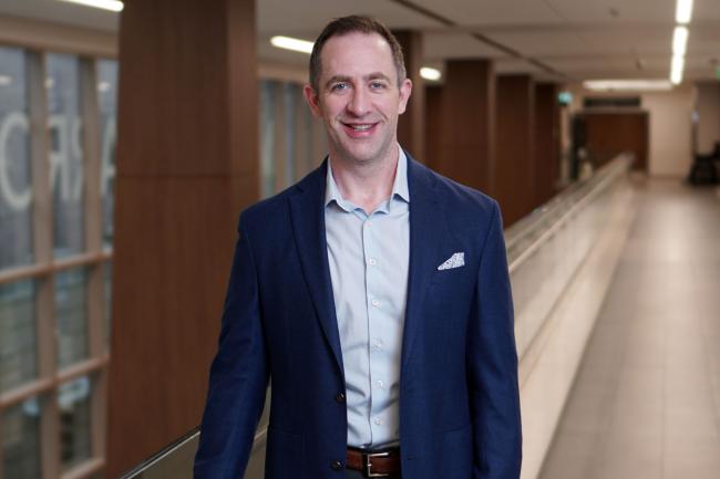 Dr. Michael Warner wearing a suit and smiling inside a hospital.