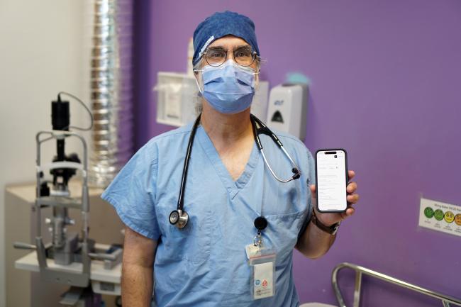 Dr. David Rosenstein, Emergency Physician and Information Technology Lead in MGH’s ED, holds a smartphone displaying the Ambient Scribe tool.
