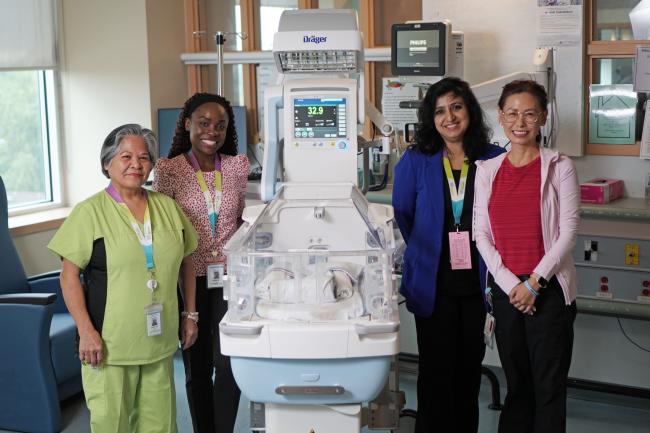 People stand and smile around the new incubator