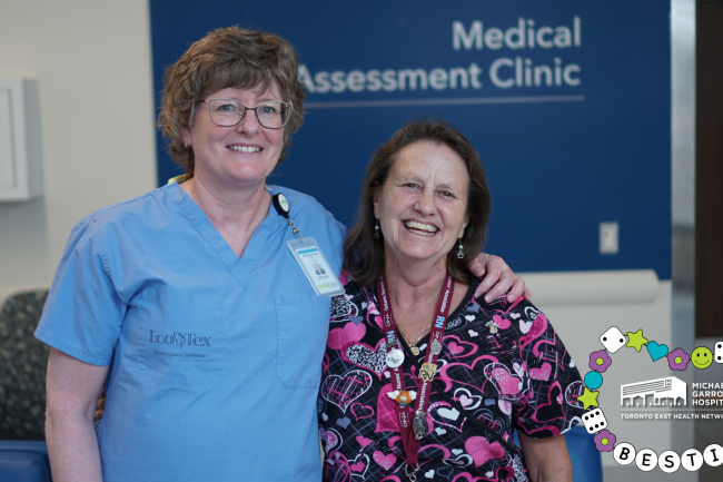 Two nurses smiling and standing next to each other. One nurse has her arm around the other.