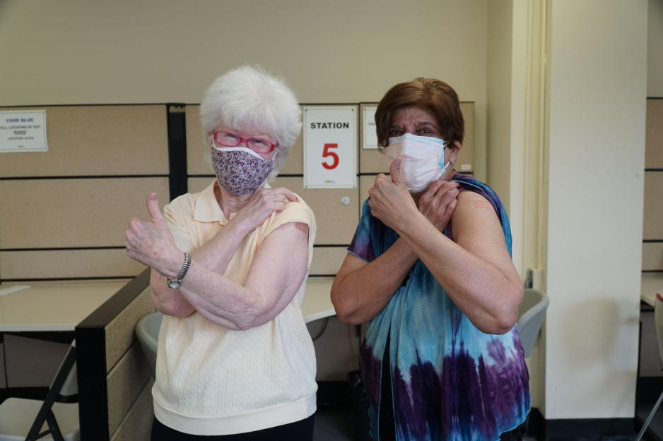 Two seniors give the thumbs up after receiving their first dose of the COVID-19 vaccine at MGH.