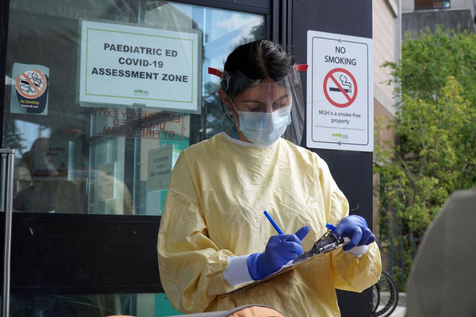 A nurse stands outside of the paediatric ed covid-19 assessment zone holding a clipboard