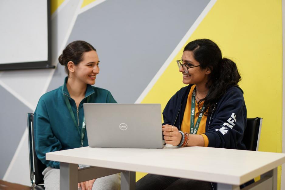 Mental health case workers sitting and smiling in front of a laptop.