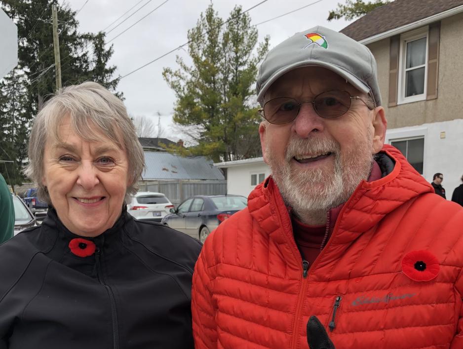 Two people smiling and standing outside.