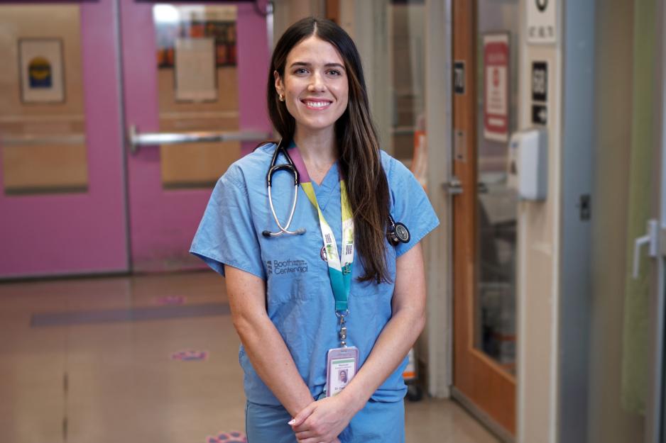 A doctor standing and smiling in a hospital hallway.